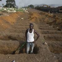 A grave digger prepares new graves at a cemetery in Freetown, Sierra Leone, on Sunday. About 40 suspected Ebola victims are being buried in this cemetery every day as the country continues to fight the epidemic. | REUTERS
