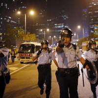 Police officers rush to disperse pro-democracy protesters attempting to block an area near the government headquarters building in Hong Kong in October. | REUTERS