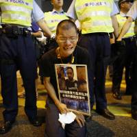 A pro-democracy protester cries as he holds a placard with photos of Ken Tsang Kin-chiu, a hospitalized protester, during a rally in front of the police headquarters of Wan Chai district in Hong Kong in October. | REUTERS