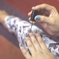 A transgender person applies nail polish to her fingernails at her office in Banda Aceh, Indonesia, on Thursday. | REUTERS