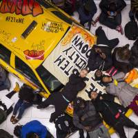 During a march in New York\'s Times Square on Sunday, protesters stage a \"die-in\" against police violence on a taxi cab on display in the Forever 21 store. | REUTERS