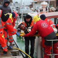 A rescued sailor is brought ashore in the harbor at Ravenna on Sunday. Three seamen were missing, feared drowned after a Turkish-registered merchant ship sank off Italy following a collision with a Belize-registered vessel in rough Adriatic seas, the coast guard said. | AFP-JIJI