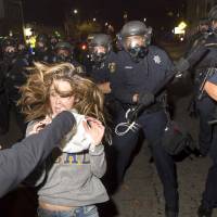 A protester flees as police officers attempt to disperse a crowd of student demonstrators during a rally against police violence at the University of Berkeley, California, early on Sunday. | REUTERS