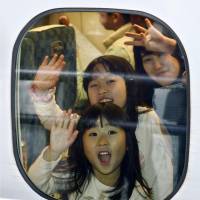 A mother and her daughters wave as they leave JR Shin-Osaka Station aboard a bullet train Saturday, the first day of the yearend holidays. | KYODO
