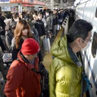 People board a bullet train at Shin-Osaka Station on Tuesday, leaving for their hometowns for the New Year\'s holidays. | KYODO