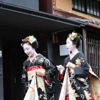 Two \"maiko,\" or apprentice geisha, pay a round of visits to their teachers of traditional Japanese arts and teahouse owners during the annual summer \"hassaku\" event in Kyoto\'s Gion district on Aug.1. | COURTESY OF DONALD KEENE