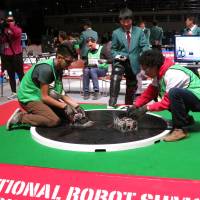A member of the Mexican team Ezimes Robots (left) and his opponent from the Colombian team Bucaros prepare for a bout in the autonomous robot division during the International Robot Sumo Tournament at Ryogoku Kokugikan in Tokyo on Sunday.  | KAZUAKI NAGATA