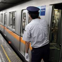A Tokyo Metro train conductor checks the platform at a subway station in October 2011. | BLOOMBERG