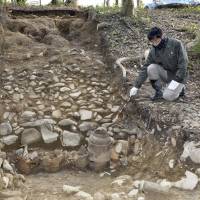 A man points to pots excavated at Tannowa Nisanzai Kofun, an ancient burial mound in the town of Misaki, Osaka Prefecture, on Friday. | KYODO