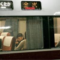 Passengers snooze aboard a Kanazawa-bound train at JR Naoetsu Station in Niigata Prefecture late Sunday. | NIIGATA NIPPO/KYODO