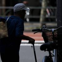 An unemployed elderly man carries his clothes to a laundromat in Tokyo, on July 8, 2013. | BLOOMBERG