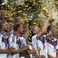 Top of the world: Andre Schuerrle lifts the World Cup as his Germany teammates watch on after beating Argentina 1-0 in the final at Rio de Janeiro\'s Maracana Stadium in July. | AFP-JIJI