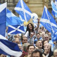 Scottish pro-independence campaigners wave Saltire flags at a \"yes\" rally in Glasgow, Scotland, on Sept. 17. | REUTERS