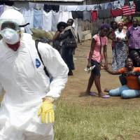 People look on as a woman wails after her husband, a suspected Ebola victim, died in the Liberian capital of Monrovia on Oct. 4. | AFP-JIJI