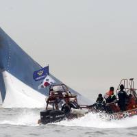 South Korean Coast Guard officers attempt to rescue passengers from the sinking Sewol ferry on April 16 after the overloaded vessel capsized near Jindo Island, off the southwest coast. | AP