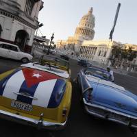 A vintage American car painted with a Cuban flag is parked near the Cuban Capitol in Havana on Dec. 18. | REUTERS