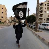 An Islamic State militant poses on a street in Raqqa, Syria, shortly after the group seized control of a city that has become the de facto capital of their so-called caliphate. | REUTERS