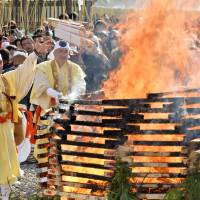 Priests throw strips of wood bearing written prayers onto a fire during the annual \"otakiage,\" or fire ceremony, Sunday at Naritasan Shinshoji Temple in Narita, Chiba Prefecture. The event was held to thank the gods for the past year. Priests burned about 50,000 strips while visitors watched. | KYODO
