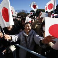 Well-wishers wave Hinomaru flags at the Imperial Palace in central Tokyo on Tuesday as they celebrate Emperor Akihito\'s 81st birthday. The Emperor called for peace and good relations with the nation\'s neighbors. | REUTERS
