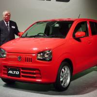Osamu Suzuki, chairman of the eponymous automaker, unveils the new Alto in Tokyo on Monday. The tiny car has outsize efficiency figures, traveling a purported 37 km on a liter of gasoline. The company says it is the most fuel-efficient vehicle of its kind. | KYODO