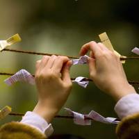 A woman ties an \"omikuji\" fortune on the first day of the new year at Meiji Shrine in Tokyo. | REUTERS