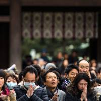 People pray and throw offerings for the upcoming year at Meiji Shrine in Tokyo on Thursday. | REUTERS