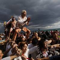 Men ride on a \"mikoshi\" or portable shrine as local people carry it into the sea during a New Year\'s festival on Thursday in Oiso, west of Tokyo. | REUTERS