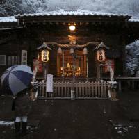 A woman holding an umbrella prays at a shrine on New Year\'s Day in Oiso, west of Tokyo. | REUTERS