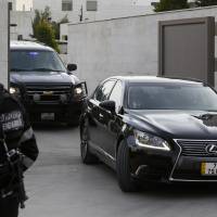 A Jordanian police stands guard as vehicles, part of a convoy carrying Japanese envoy, State Minister for Foreign Affairs Yasuhide Nakayama, leave the Japanese Embassy in Amman Saturday.  | REUTERS
