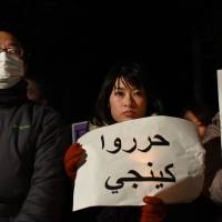 People hold messages written in Arabic during a demonstration Wednesday evening in front of the prime minister\'s office. | FINBAR O\'MALLON
