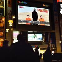 People look at a large TV screen near Shinjuku Station in Tokyo on Jan. 20, showing news reports about two Japanese men who have been kidnapped by the Islamic State group. | AFP-JIJI