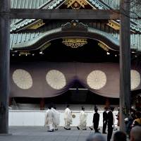Shinto priests walk in a line at Yasukuni Shrine in Tokyo on Thursday as visitors watch and celebrate the new year. | AFP-JIJI