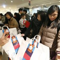 A tourist from Hong Kong (right) joins a crowd of shoppers grabbing \"fukubukuro\" (lucky bags) at the Mitsukoshi department store in Tokyo\'s Ginza district on Jan. 2. | KYODO