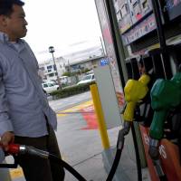 A motorist fills up his car at a gasoline station in the outskirts of Tokyo. | C. PERTWEE/BLOOMBERG