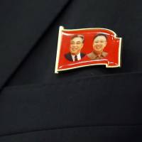 A pin worn by a North Korean tourism envoy depicting former leaders Kim Il Sung and Kim Jong Il is seen in Bern on Thursday. The North is thought to have pressured Myanmar to crack down on illegal sales of bootlegged DVDs of Sony\'s movie \"The Interview\" in Yangon, Myanmar\'s commercial epicenter. | REUTERS