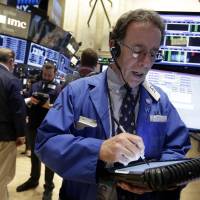 Trader Sal Suarino works on the floor of the New York Stock Exchange on Monday, when U.S. stocks opened lower, led by declines in energy stocks as the price of oil plunged again. | AP
