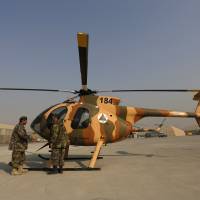 Members of the Afghan Air Force crew stand next to a helicopter at the military airport in Kabul on Dec. 18. With new planes capable of engaging Taliban insurgents delayed by over two years, and NATO air missions backing up troops on the ground now at a minimum, the fledgling Afghan Air Force is scrambling to provide even basic support. | REUTERS