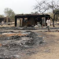 Children stand outside a charrred house in the Nigerian town of Baga in 2013 after two days of clashes between soldiers of the Joint Task Force and members of the Islamist sect Boko Haram, which launched new deady attacks in the restive region this week. | AFP-JIJI