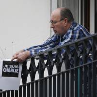 A resident holds a placard reading \"I am Charlie\" on a Paris balcony near the scene of the Wednesday massacre at the weekly Charlie Hebdo. The U.S. Embassy posted online the same message of solidarity with the victimized magazine. | REUTERS