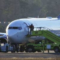 A worker closes the door to a Delta Airlines airplane sitting on the tarmac at Hartsfield-Jackson Atlanta International Airport in Atlanta on Saturday. Police searched the Delta airplane and a Southwest airplane at Atlanta\'s main airport after authorities received what they described as \"credible\" bomb threats. | AP
