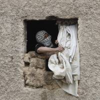 A Palestinian woman fixes a window cover at her house in the West Bank Beduin village of Almaleh, in the northern Jordan Valley, on Tuesday ahead of a forecast blizzard. | REUTERS