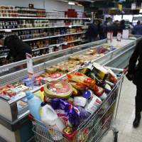 A woman walks near a shopping cart full of products in a supermarket in Jerusalem on Tuesday as people stock up on supplies before heavy snow hits the Holy Land. | REUTERS