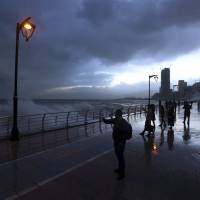 Residents walk along the seaside promenade and snap photographs of waves slamming into the seawall in Beirut on Tuesday. A powerful winter storm began striking across the Middle Eas, bringing a bitter cold to Syrian refugees huddled in Lebanon and blanketing Cairo in a sandstorm. | AP