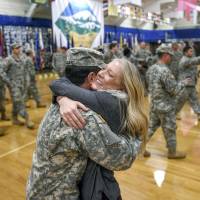 Ashley Maggard embraces her husband, U.S. Army 1st Lt. Kyle Maggard, after he returned from Liberia to help with the U.S. response to the Ebola outbreak, Thursday at the Fort Carson Special Events Center in Colorado Springs, Colorado. Maggard and other soldiers with the 4th Engineer Battalion were held at Joint Base Lewis-McChord for a 21-day monitoring period before returning home. | AP