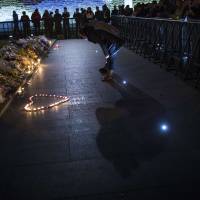 People hold a memorial ceremony Thursday for those killed in a fatal crush during a New Year\'s Eve celebration on the Bund, in Shanghai. The stampede killed at least 36 people, authorities said, possibly caused by people rushing to pick up fake money thrown from a building. | REUTERS