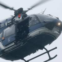 A helicopter with members of the French intervention gendarme forces hover above the scene of a hostage-taking Friday at an industrial zone in Dammartin-en-Goele. | REUTERS