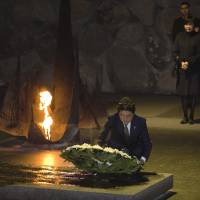 Prime Minister Shinzo Abe lays a wreath as his wife, Akie, stands behind him during a ceremony in the Hall of Remembrance at the Yad Vashem Holocaust memorial in Jerusalem on Monday | REUTERS
