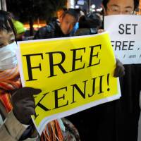 People hold up \"Free Kenji\" signs calling for the release of Islamic State captive Kenji Goto on Wednesday evening in front of the prime minister\'s office. | SATOKO KAWASAKI