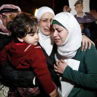 Anwar Tarawneh (right), the wife of Islamic State captive Jordanian pilot Lt. Muath al-Kasaesbeh, and his sister (center) weep after listening to a statement Wednesday released by Islamic State in front of the Royal Palace in Amman. Jordan is still holding Iraqi terrorist Sajida al-Rishawi, whose release has been demanded by Islamic State militants and her freedom depends on Kasaesbeh\'s fate. | REUTERS