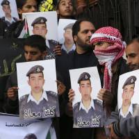 Activists in Amman on Monday hold up pictures of pilot Muath al-Kasasbeh, a captive of the Islamic State group, whose plane went down in Syria last month. Jordan\'s King Abdullah is quoted as saying the pilot\'s life is a national priority. | REUTERS